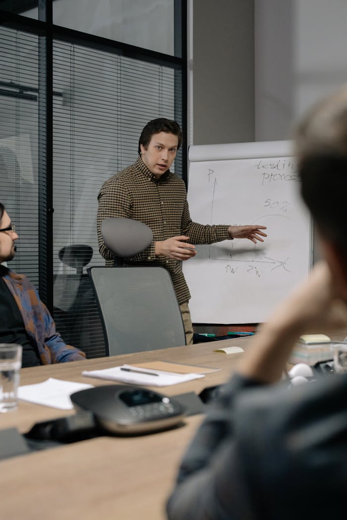Businessman giving a presentation to colleagues in modern office setting, emphasizing teamwork and communication.